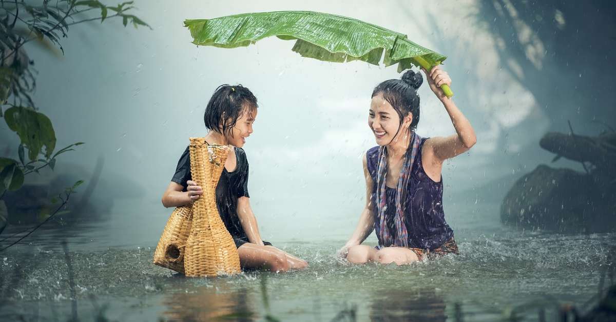 seorang wanita dan anak kecil sedang bermain hujan di sungai