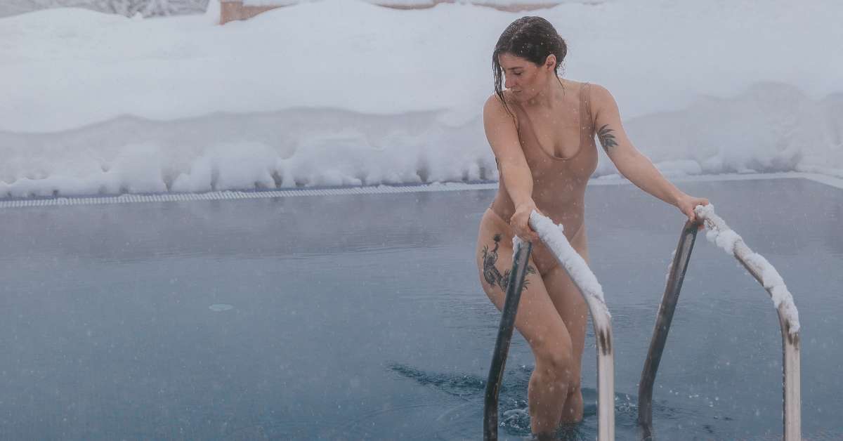 Seorang wanita bertato keluar dari kolam renang di cuaca dingin bersalju