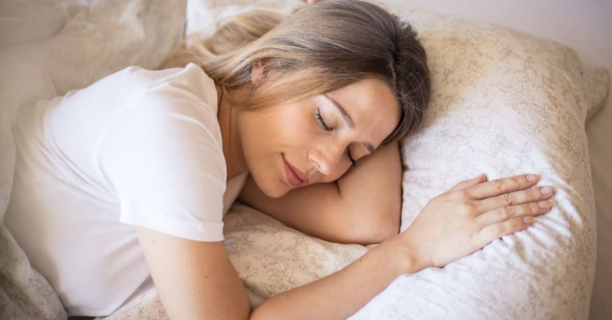 Seorang wanita tertidur dengan nyenyak di kasur putih